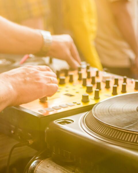 A DJ is mixing music on turntables and a mixer at an outdoor event.