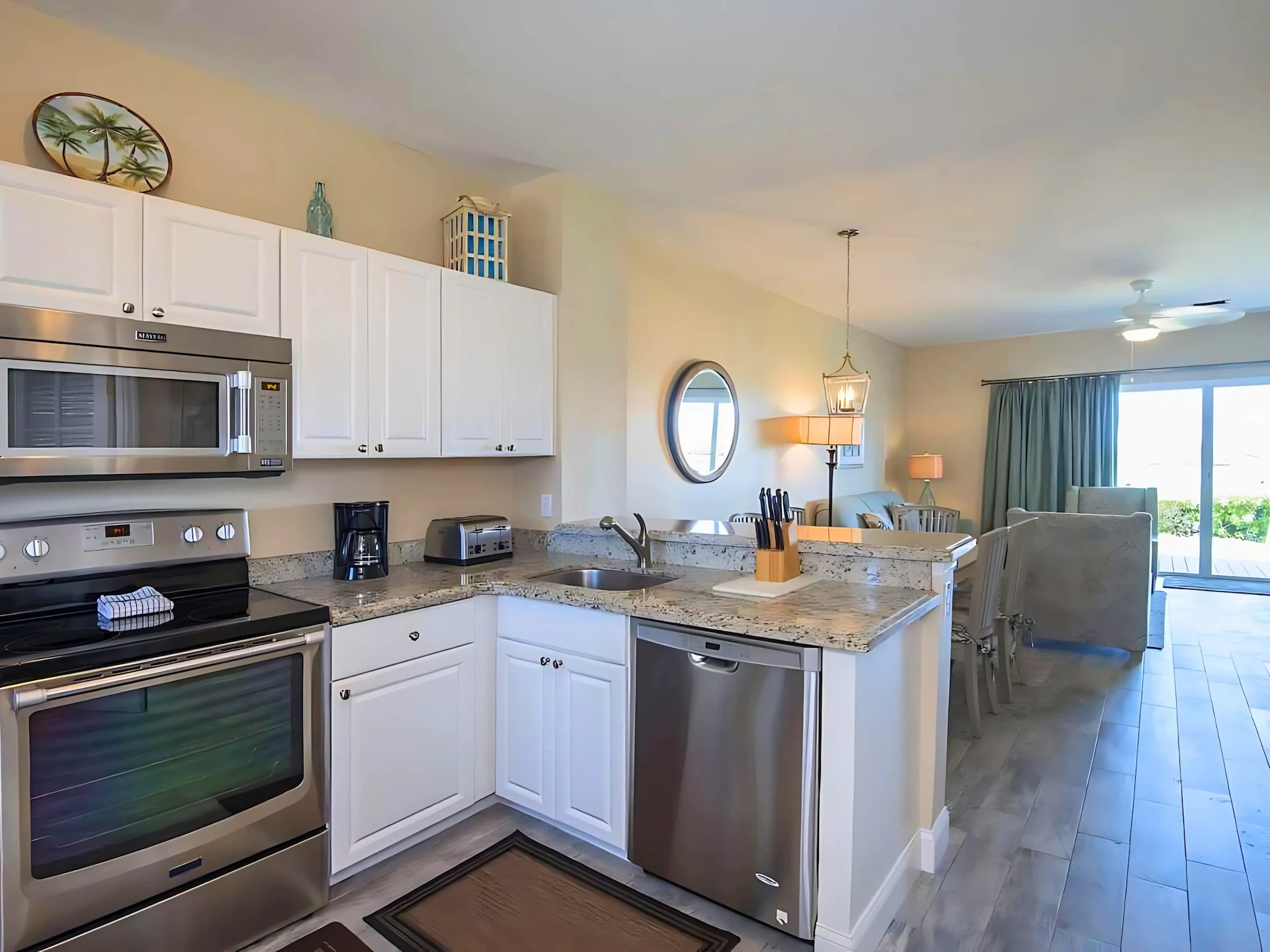 Open-concept coastal kitchen and dining area with white cabinets, stainless appliances, and beach-themed decor.