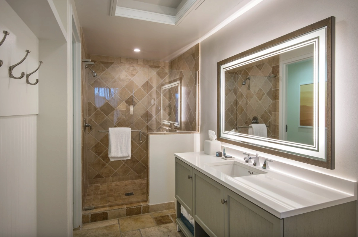 Sleek bathroom with walk-in shower, LED mirror, and double vanity with white countertop.