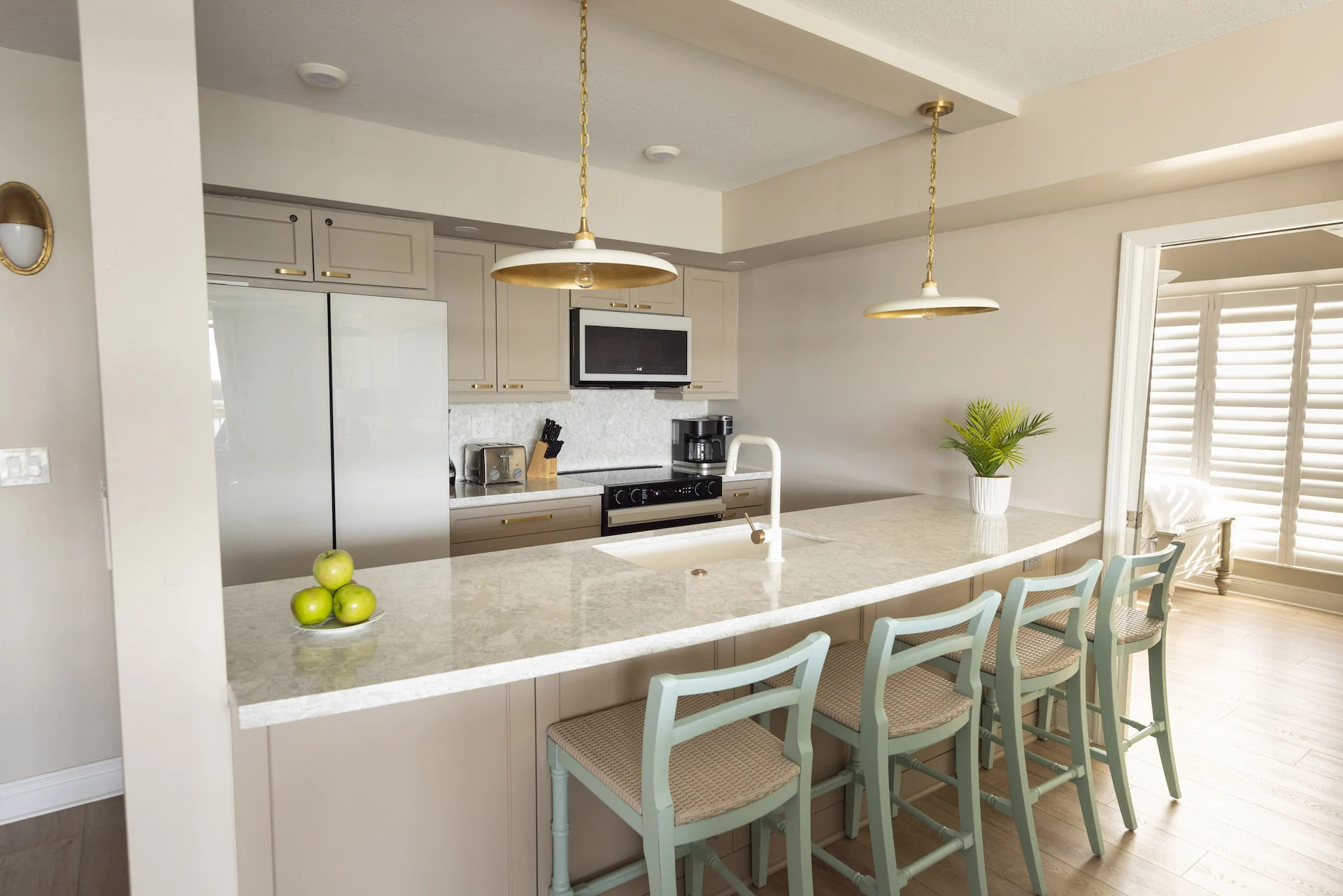 Modern kitchen with marble island, light blue bar stools, pendant lights, and stainless steel appliances.