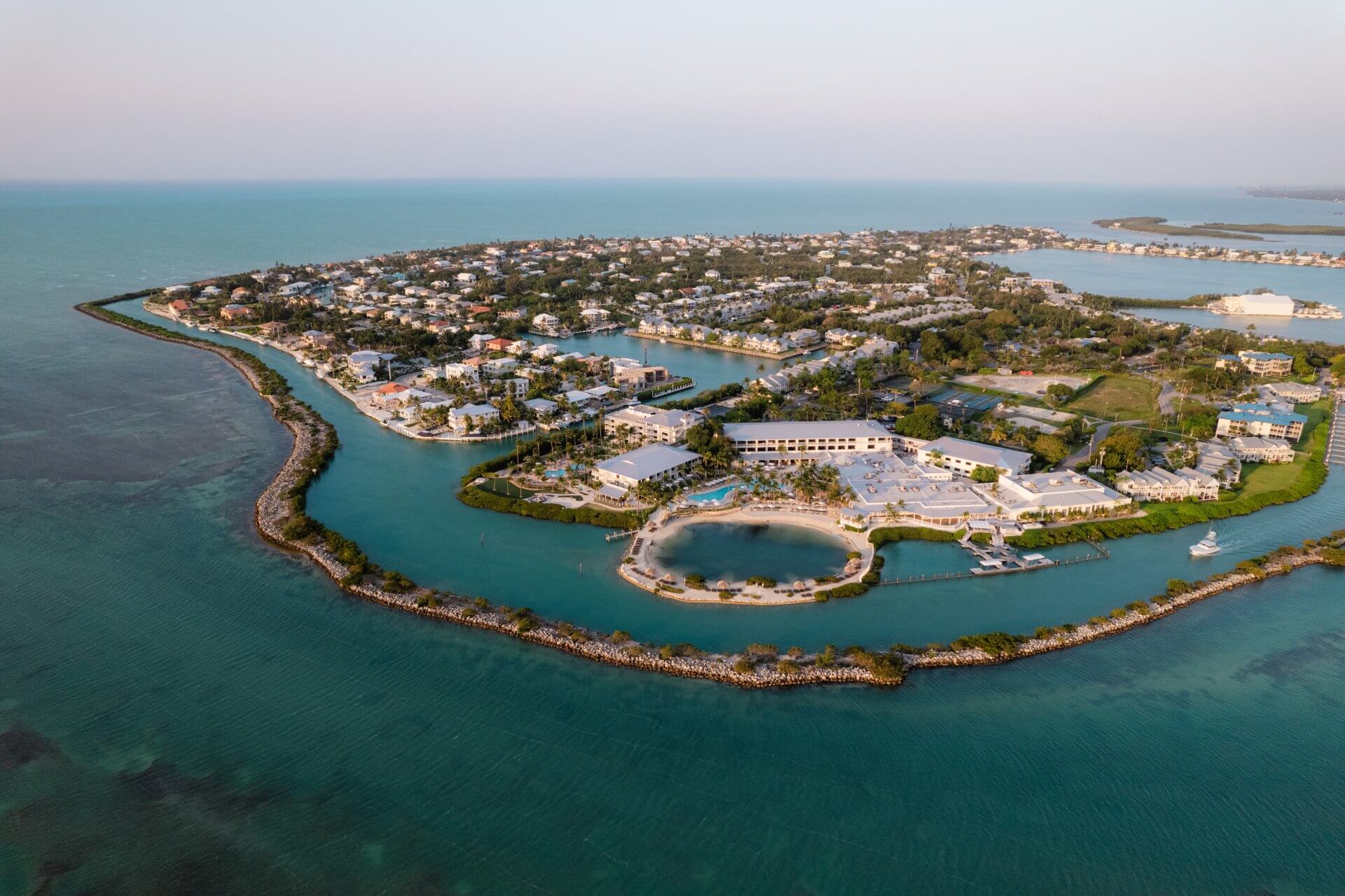 Aerial view of a tropical island resort surrounded by turquoise waters, lush greenery, and serene coastal charm.