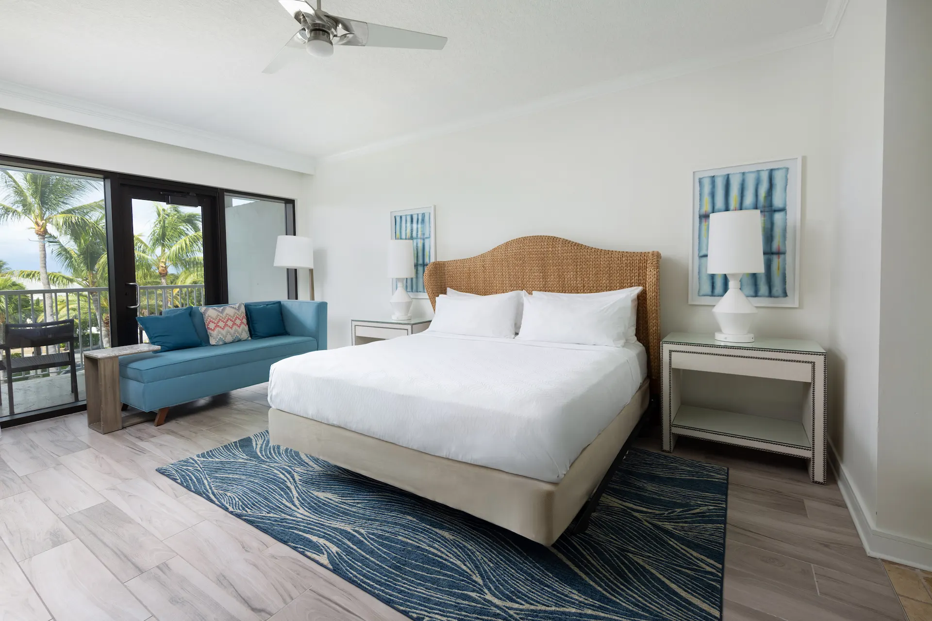 Bright hotel room with rattan headboard, blue sofa, and balcony view at Hawks Cay Resort.