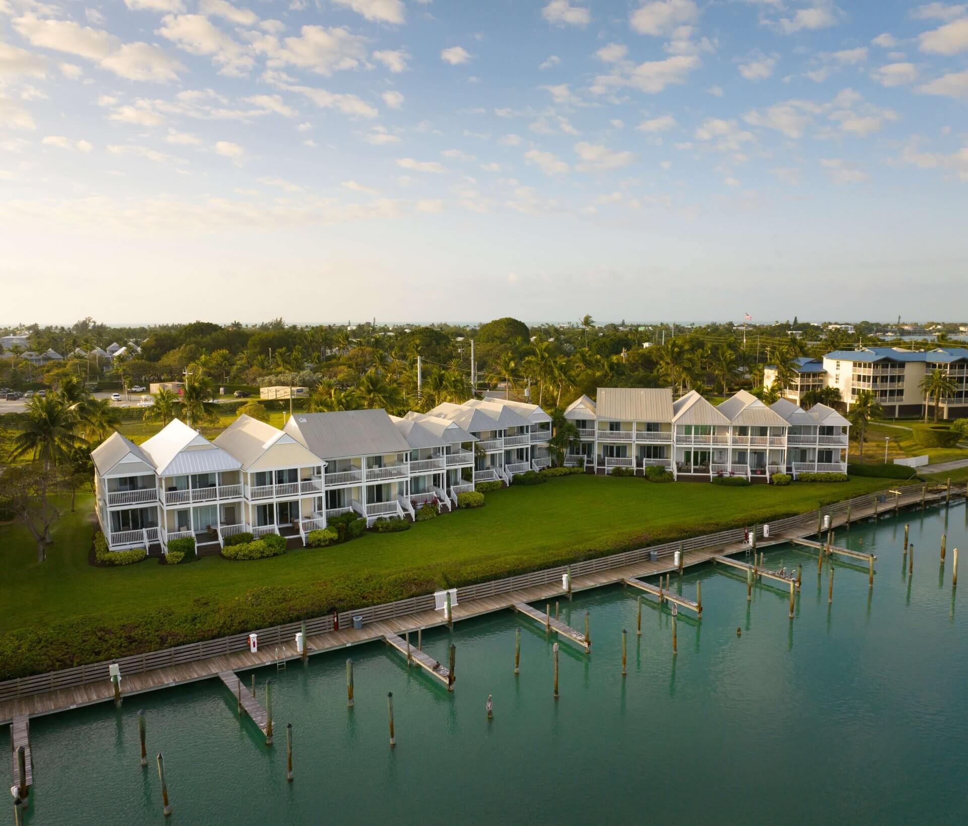 Waterfront resort cottages with private docks, lush lawns, and calm marina views under a soft coastal sky.